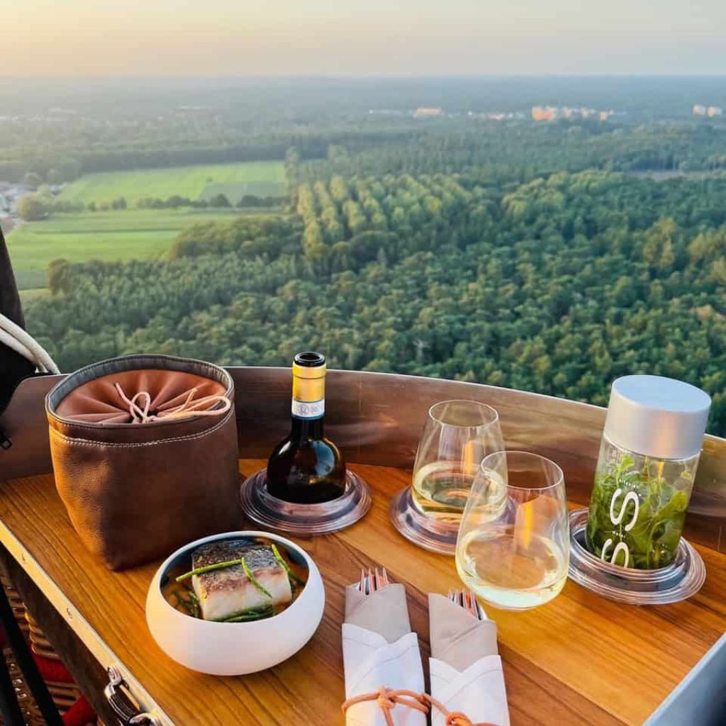 Exclusief luchtballondiner: gasten genieten van een gastronomisch menu op grote hoogte tijdens een incentive boven de Veluwe.