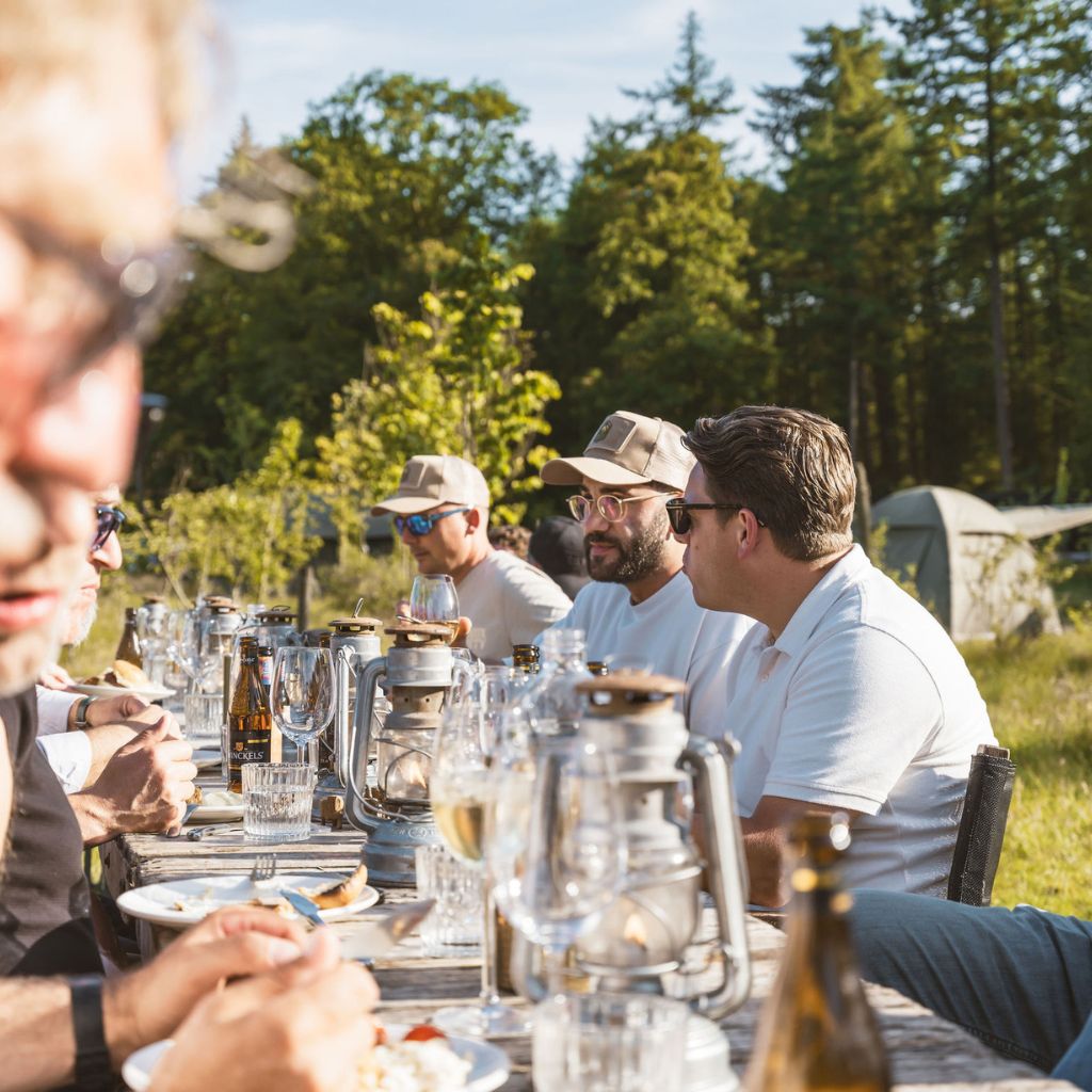 Wild diner aan lange tafel tijdens zakelijk event in de natuur